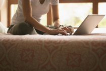 Frau benutzt Laptop auf Bett im Schlafzimmer zu Hause — Stockfoto