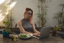 Jeune femme utilisant un ordinateur portable au café — Photo de stock