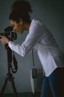 Жіночий фотограф, який натискає фотографії з цифровою камерою у фотостудії — стокове фото