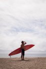 Surfista di sesso maschile che tiene la tavola da surf in spiaggia — Foto stock