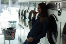 Mujer sonriente hablando por teléfono en la lavandería - foto de stock