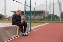 Sportlerin benutzte Handy auf Laufstrecke — Stockfoto