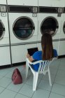 Vista trasera de la mujer que usa el ordenador portátil en la lavandería - foto de stock