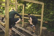 Dos hombres haciendo ejercicio en la pista de obstáculos en el campo de entrenamiento - foto de stock