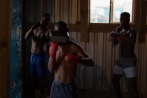 Boxer masculino usando fone de ouvido de realidade virtual enquanto pratica boxe no estúdio de fitness — Fotografia de Stock
