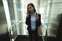 Donna d'affari sorridente che parla al cellulare in ufficio — Foto stock
