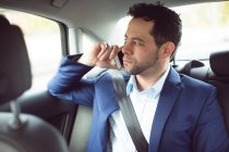 Бизнесмен разговаривает по мобильному телефону в современной машине — стоковое фото