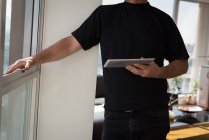 Sezione centrale dell'uomo in piedi con tablet digitale a casa — Foto stock