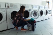 Mujer joven con cesta llena de ropa en lavadero - foto de stock