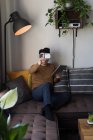 Casque homme en réalité virtuelle utilisant une tablette numérique dans le salon à la maison — Photo de stock