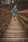 Junger Mann streckt sich auf Holzbrücke im Wald — Stockfoto