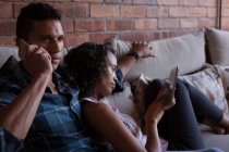 Пара використовує цифровий планшет і розмовляє на мобільному телефоні вдома — стокове фото