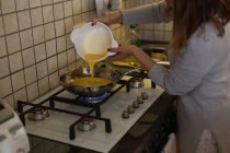 Mulher preparando omelete na cozinha em casa — Fotografia de Stock