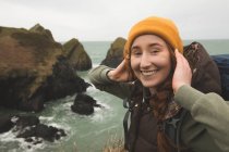 Beautiful smiling female hiker standing near sea coast — Stock Photo