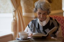 Seniorin liest zu Hause ein Buch — Stockfoto