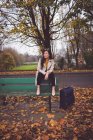 Задумчивая деловая женщина сидит на скамейке запасных осенью — стоковое фото