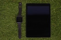 Smartwatch e tablet digital na grama artificial — Fotografia de Stock
