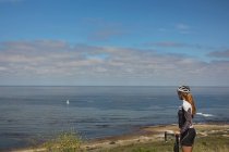 Велосипедистка с горным велосипедом смотрит на море в солнечный день — стоковое фото