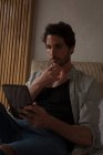 Homme utilisant une tablette numérique dans la chambre à coucher à la maison — Photo de stock