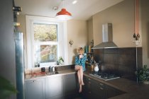 Jovem mulher tendo na cozinha em casa — Fotografia de Stock