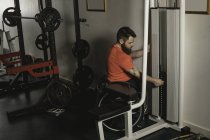 Людина з обмеженими можливостями на інвалідному візку збільшує вагу вправ, що тягнуться в спортзалі — стокове фото