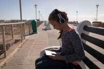 Дівчина використовує цифровий планшет на тротуарі в сонячний день — стокове фото