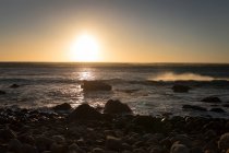 Закат над каменистым морским берегом — стоковое фото