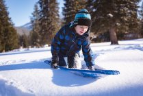 Милий хлопчик грає з упряжках у снігу взимку — стокове фото
