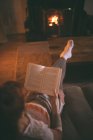 Mujer leyendo un libro en la sala de estar en casa - foto de stock