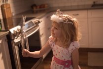 Fille en couronne avec bâton magique à la maison — Photo de stock