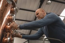 Männliche Arbeiter überprüfen Maschine der Brennerei in Fabrik — Stockfoto