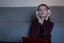 Молода жінка слухає музику у вітальні вдома — стокове фото