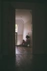 Femme réfléchie assise sur le sol en bois à la maison — Photo de stock