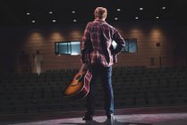 Man standing with guitar on stage at theatre. — Stock Photo