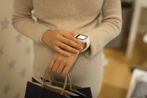 Pregnant woman using smartwatch in store — Stock Photo