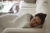 Женщина, завернутая в одеяло, спит дома на диване — стоковое фото