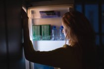 Donna che apre un frigorifero a casa — Foto stock
