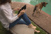 Женщина с помощью цифрового планшета возле бассейна — стоковое фото