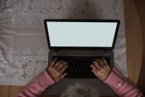 Активна старша жінка використовує ноутбук вдома — стокове фото