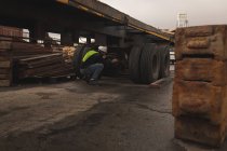 Работник дока проверяет шину грузовика на верфи — стоковое фото