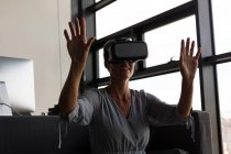 Femme d'affaires mature utilisant un casque de réalité virtuelle dans le bureau — Photo de stock