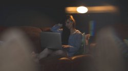 Donna che utilizza il computer portatile sul divano in soggiorno a casa — Foto stock