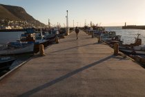 Жінка ходить на причалі біля причальних човнів на сонячному світлі — стокове фото