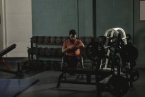 Homem deficiente assistindo tempo no relógio de pulso no ginásio — Stock Photo