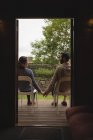 Rear view of couple holding hands while sitting on chairs — Stock Photo