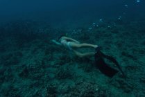 Mulher snorkeling subaquático no mar sobre fundo rochoso — Fotografia de Stock