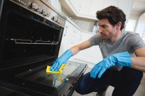Мужчина чистит газовую плиту на кухне дома — стоковое фото