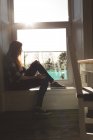 Задумчивая женщина сидит у окна дома — стоковое фото