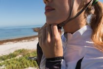 Primo piano di motociclista donna che indossa il casco vicino alla spiaggia in una giornata di sole — Foto stock