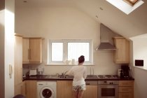 Visão traseira da mulher que trabalha no interior da cozinha em casa
. — Fotografia de Stock